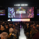 People sitting in a large room filled with large screens at Star Wars Celebration 2019.